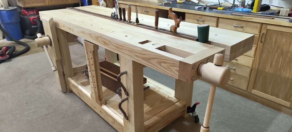 Roubo workbench from ash, with maple leg vise and wagon vise, with walnut tool insert.